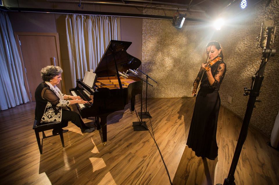 Imagem das integrantes do Duo Almeida Prado tocando em um estúdio.